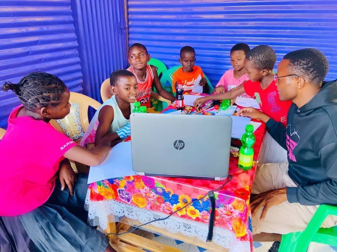 Young learners gathered around a laptop